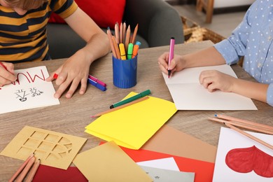 Photo of Children making beautiful greeting cards at table indoors, closeup