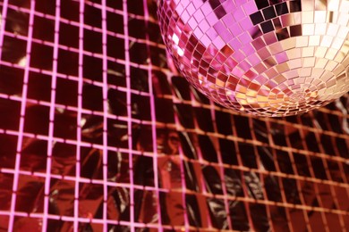 Photo of Shiny disco ball against foil party curtain under pink light, space for text