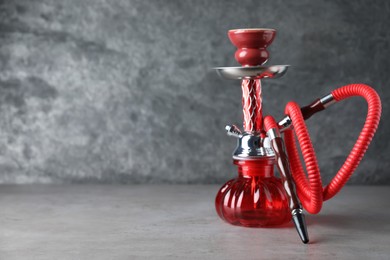 Photo of Modern red hookah on grey table, space for text