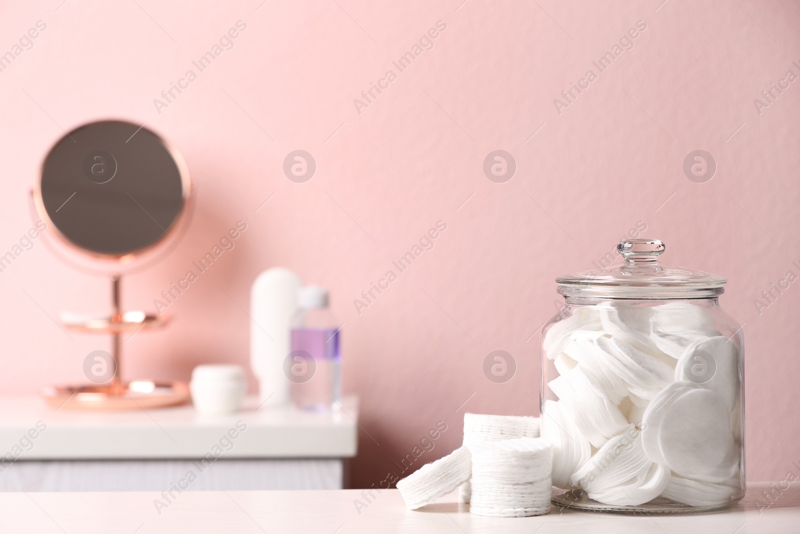 Photo of Glass jar with cotton pads on table in bathroom, space for text