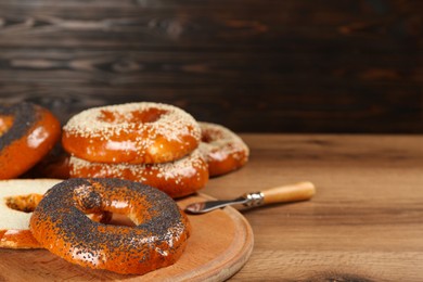 Many delicious fresh bagels on wooden table, space for text