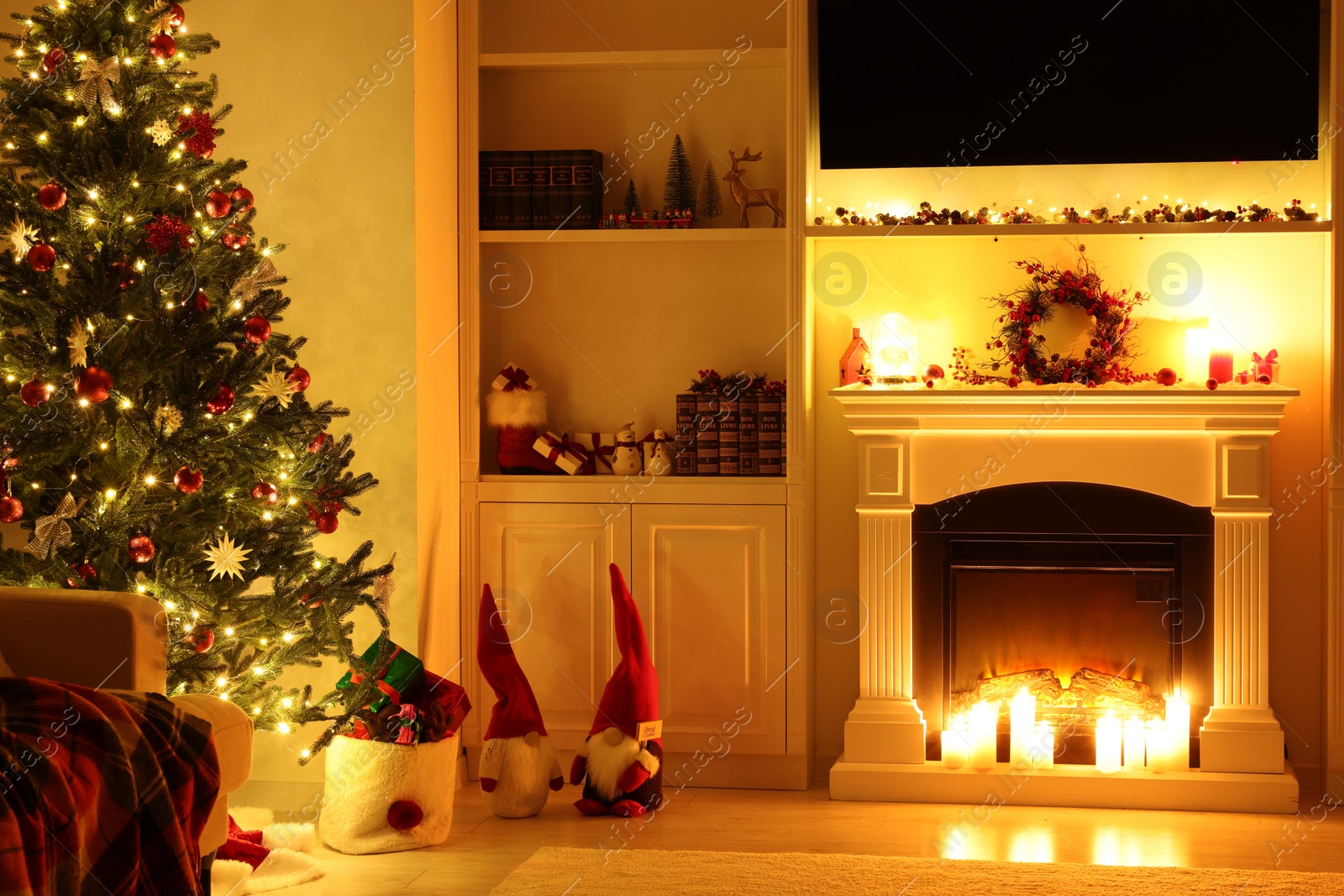 Photo of Cosy room with fireplace and burning candles. Christmas atmosphere