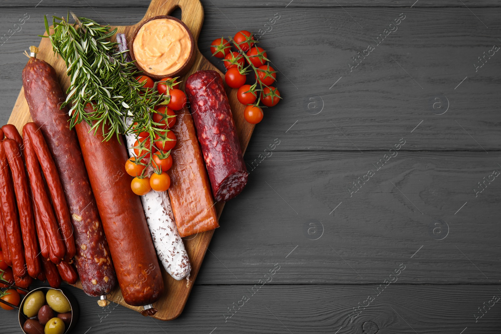 Photo of Different types of tasty sausages on grey wooden table, flat lay. Space for text