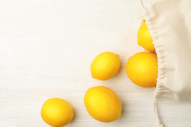 Photo of Cotton eco bag with lemons on white wooden background, flat lay. Space for text