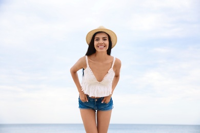 Beautiful young woman with beach hat near sea