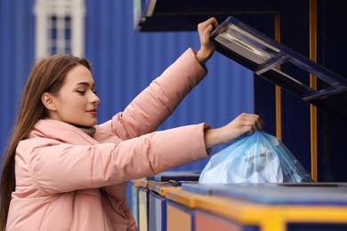 Photo of Woman throwing garbage into bin at recycling point outdoors