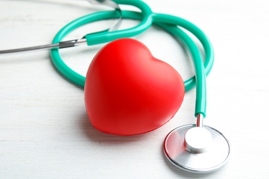 Photo of Stethoscope and red heart on wooden background. Cardiology concept