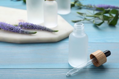 Photo of Bottle of essential oil on light blue wooden table, closeup. Space for text