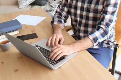 Young man working with laptop at desk. Home office