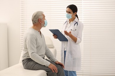 Nurse with clipboard talking to elderly patient in hospital