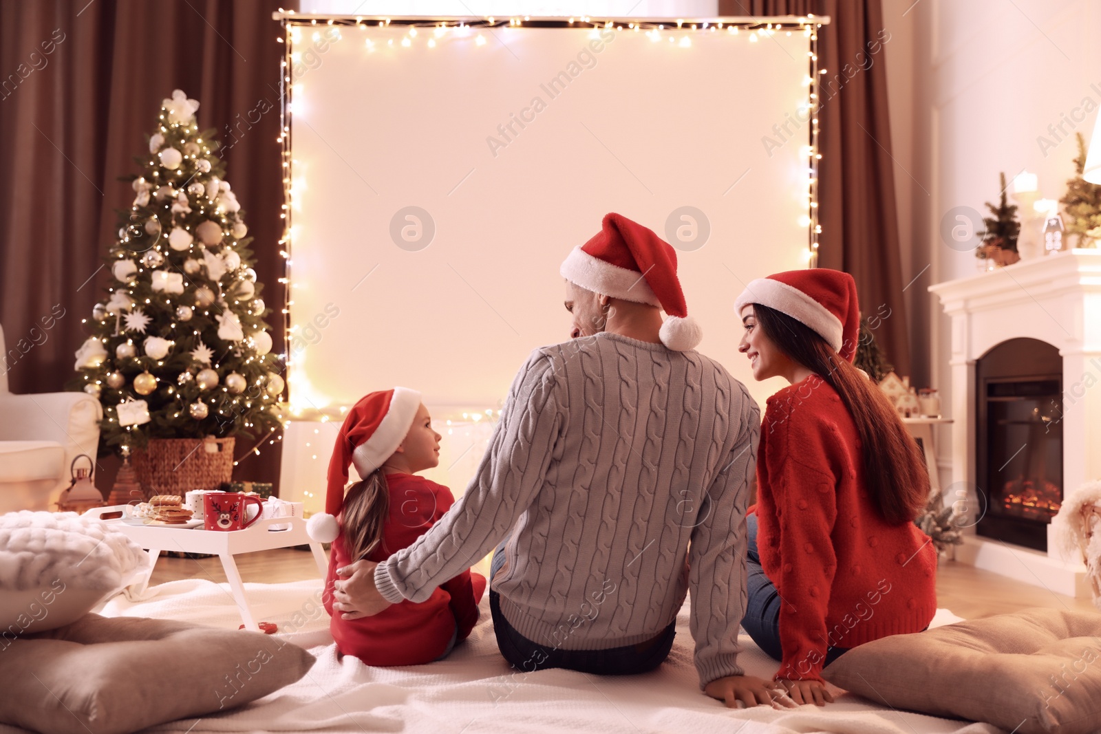 Photo of Family watching movie using video projector at home. Cozy Christmas atmosphere