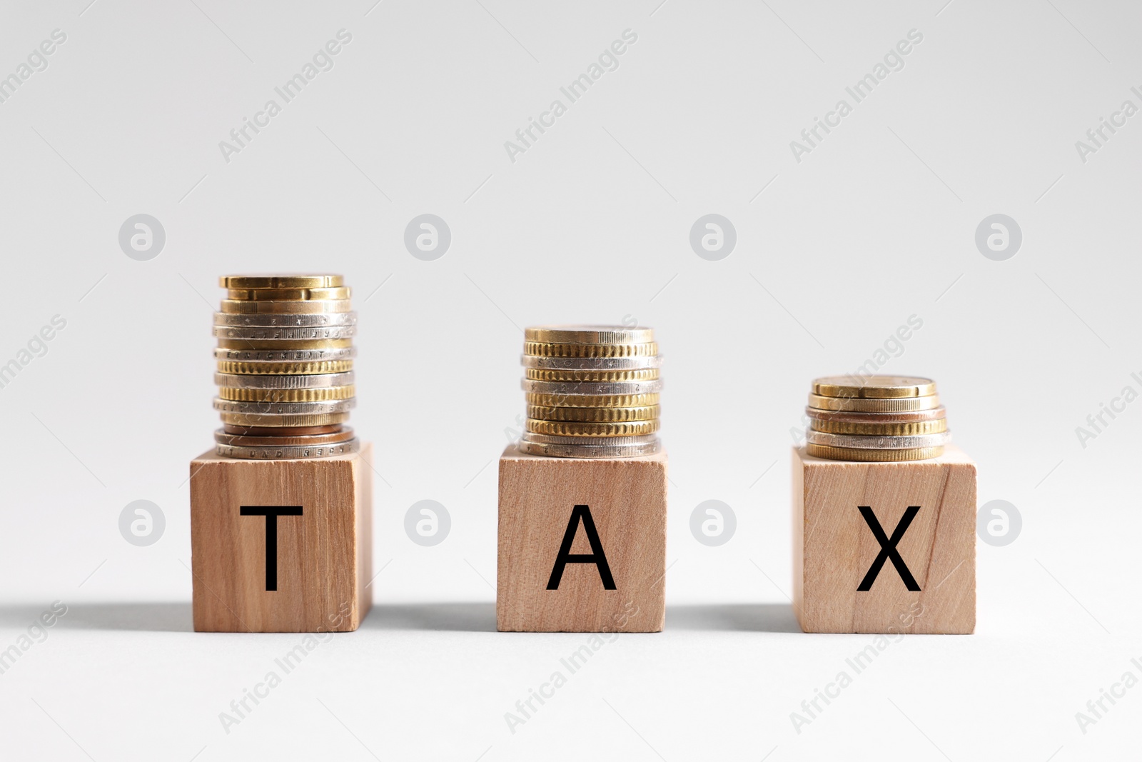 Photo of Word Tax made of wooden cubes and coins on white background