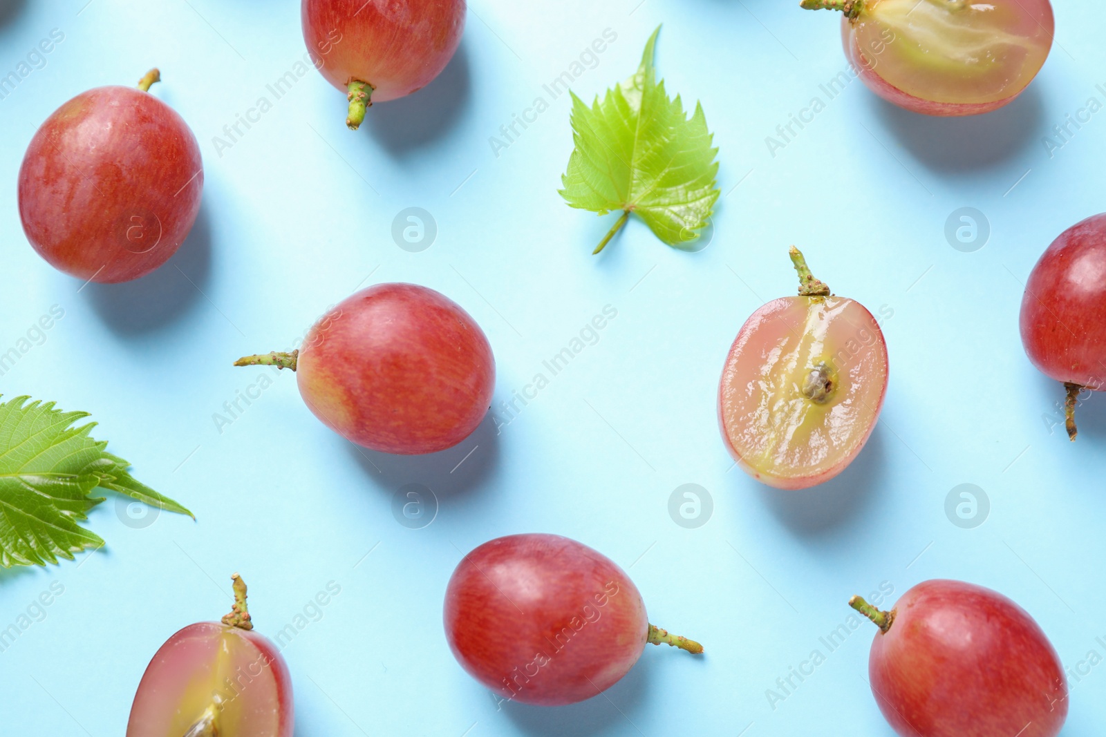 Photo of Flat lay composition with fresh ripe juicy grapes on light blue background