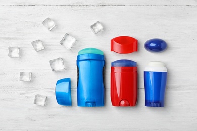 Photo of Different deodorants and ice cubes on light wooden background