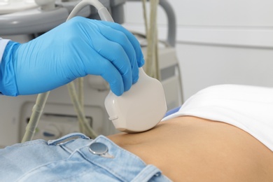 Photo of Doctor conducting ultrasound examination of patient's abdomen in clinic, closeup
