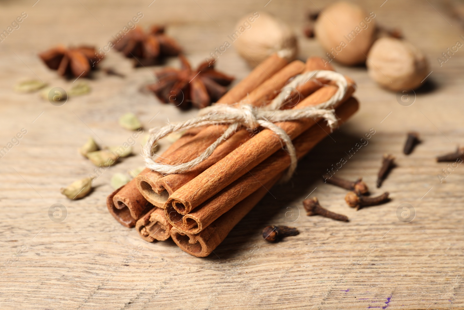 Photo of Cinnamon sticks and other spices on wooden table, closeup