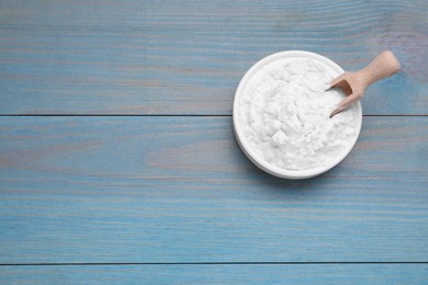 Photo of Bowl and scoop of natural starch on light blue wooden table, top view. Space for text