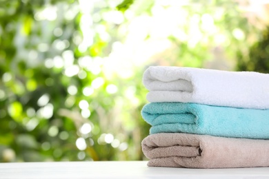 Stack of clean soft towels on table against blurred background. Space for text