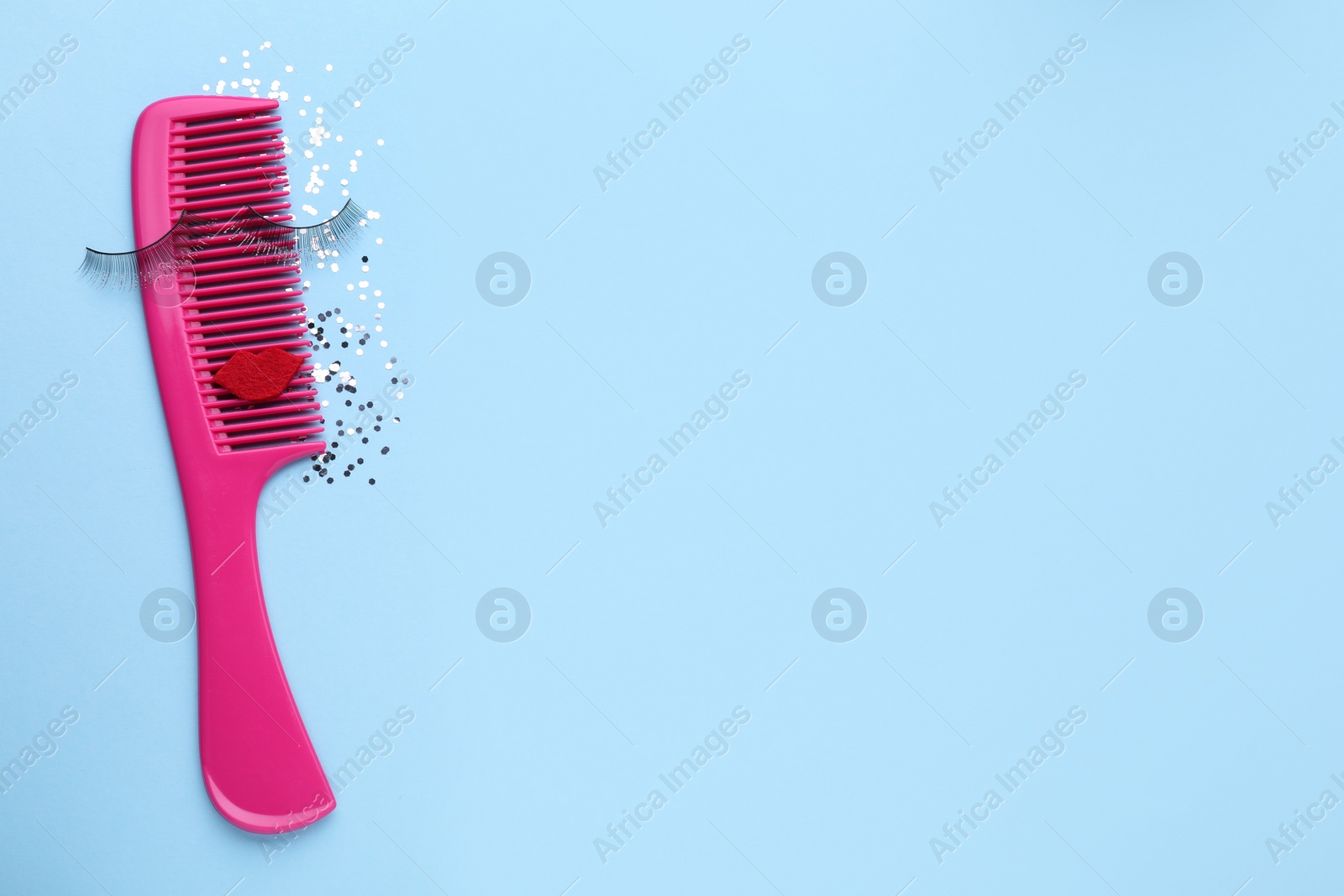 Photo of Hair comb with false eyelashes, red lips and confetti on light blue background, flat lay. Space for text
