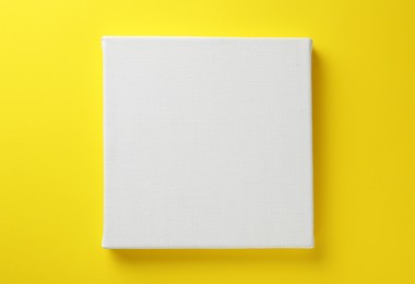 Photo of Blank canvas on yellow background, space for text