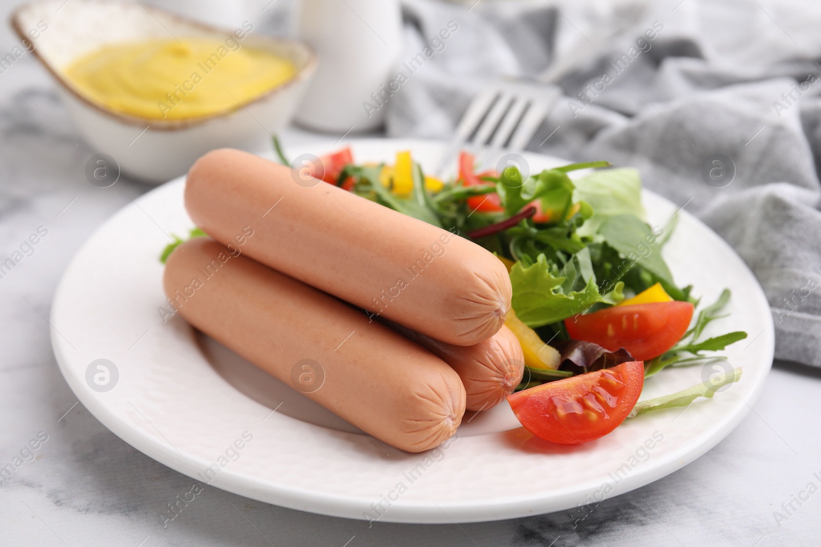 Photo of Delicious boiled sausages with salad on table