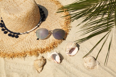 Photo of Straw hat and sunglasses on sand, above view. Beach accessories