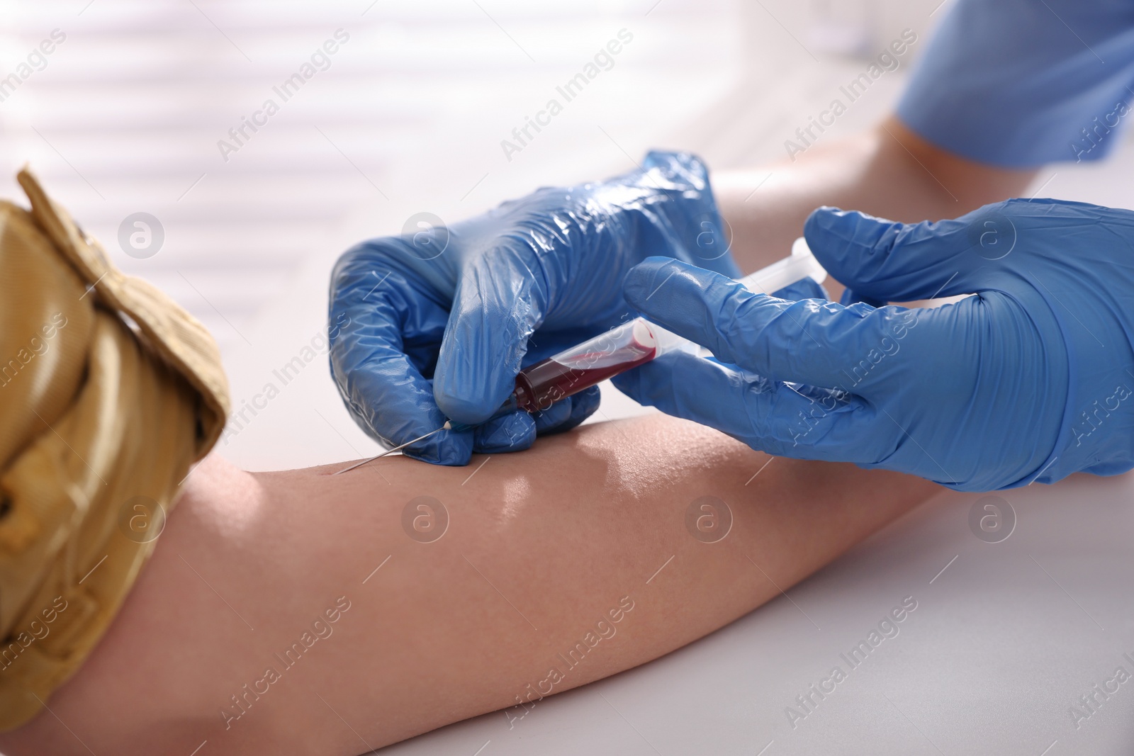 Photo of Doctor drawing blood sample of patient with syringe in hospital, closeup