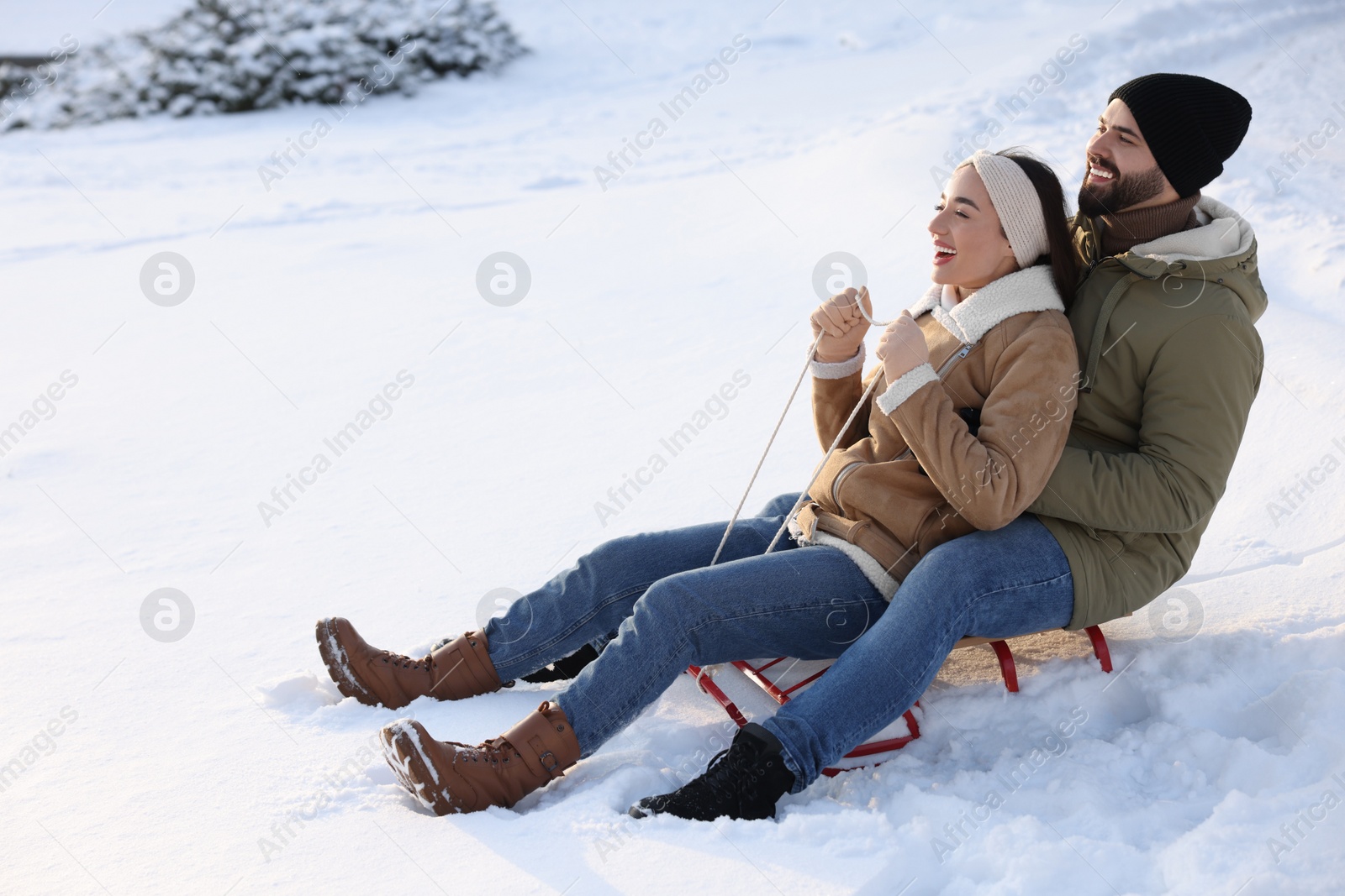 Photo of Happy young couple sledding outdoors on winter day