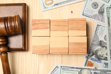 Tax law. Blank cubes, gavel and dollar banknotes on wooden table, flat lay