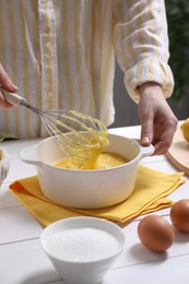 Woman cooking lemon curd at white wooden table, closeup