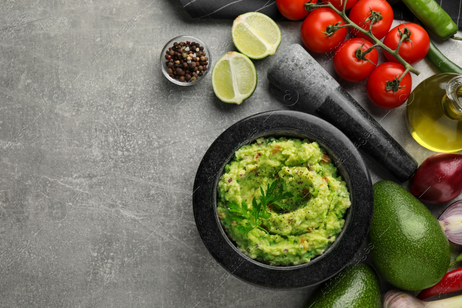 Photo of Delicious guacamole and ingredients on grey table, flat lay. Space for text