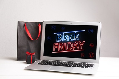 Laptop, shopping bag and gift box on white table. Black Friday Sale online