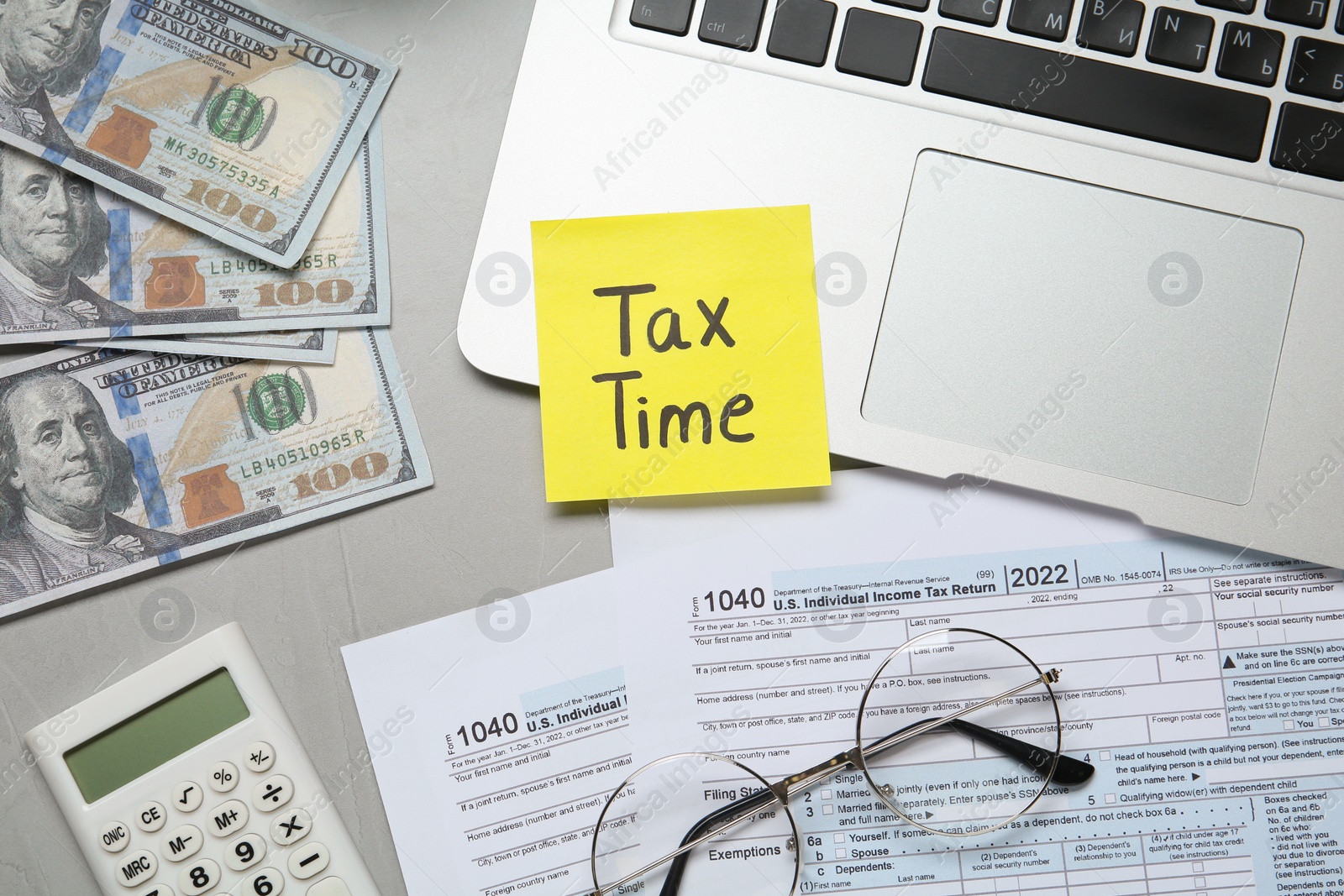 Photo of Reminder note with words Tax Time, documents, laptop, money and calculator on grey table, flat lay