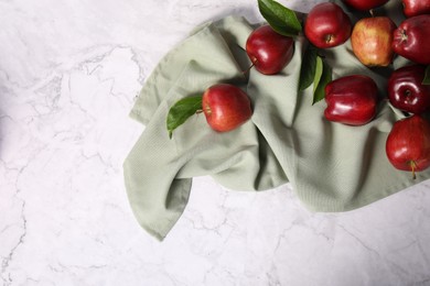 Photo of Fresh ripe red apples with leaves on white marble table, flat lay. Space for text