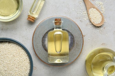 Sesame oil and seeds on light grey table, flat lay