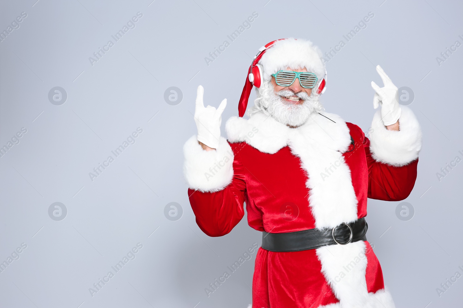 Photo of Santa Claus listening to Christmas music on color background