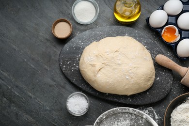 Fresh yeast dough and ingredients on black table, flat lay. Space for text