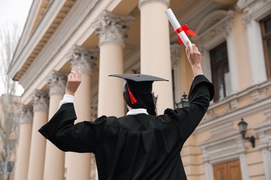 Student with diploma after graduation ceremony outdoors, back view