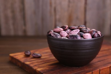 Bowl with dry kidney beans on wooden table, closeup. Space for text