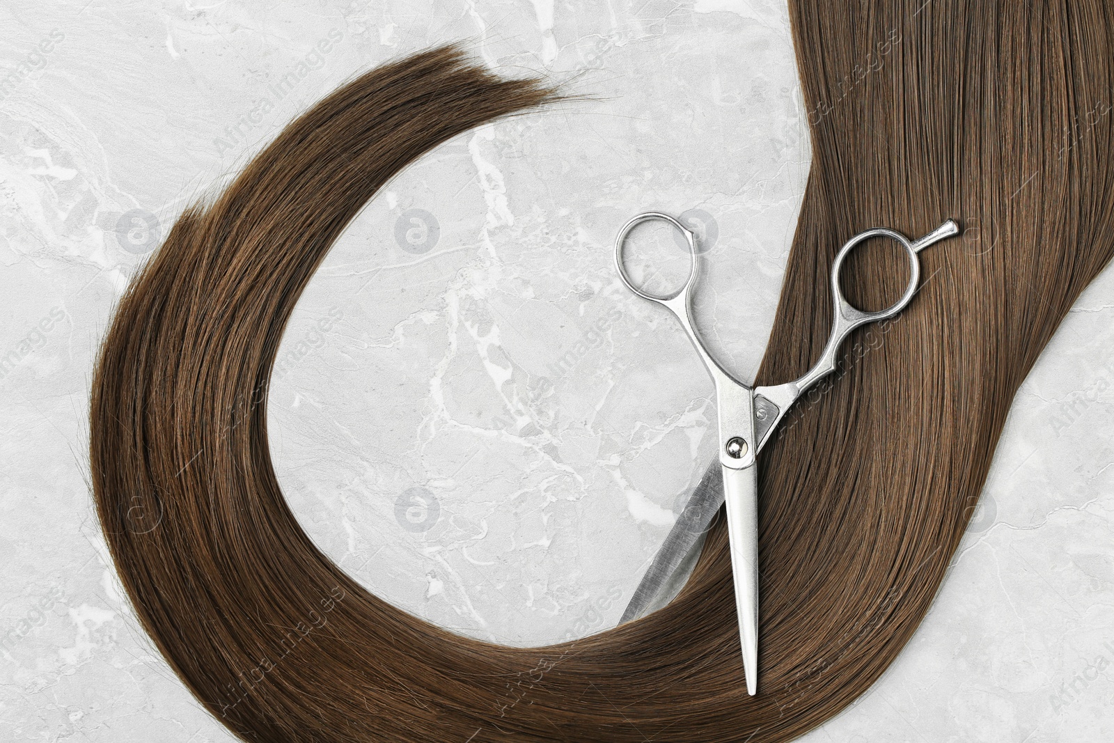 Photo of Flat lay composition with brown hair and scissors on grey background. Hairdresser service