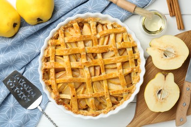 Tasty homemade quince pie, cake server and fresh fruits on white wooden table, flat lay