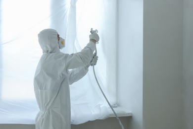 Photo of Decorator painting window slope with spray indoors