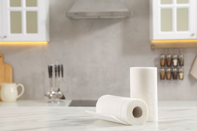Photo of Rolls of paper towels on white marble table in kitchen. Space for text