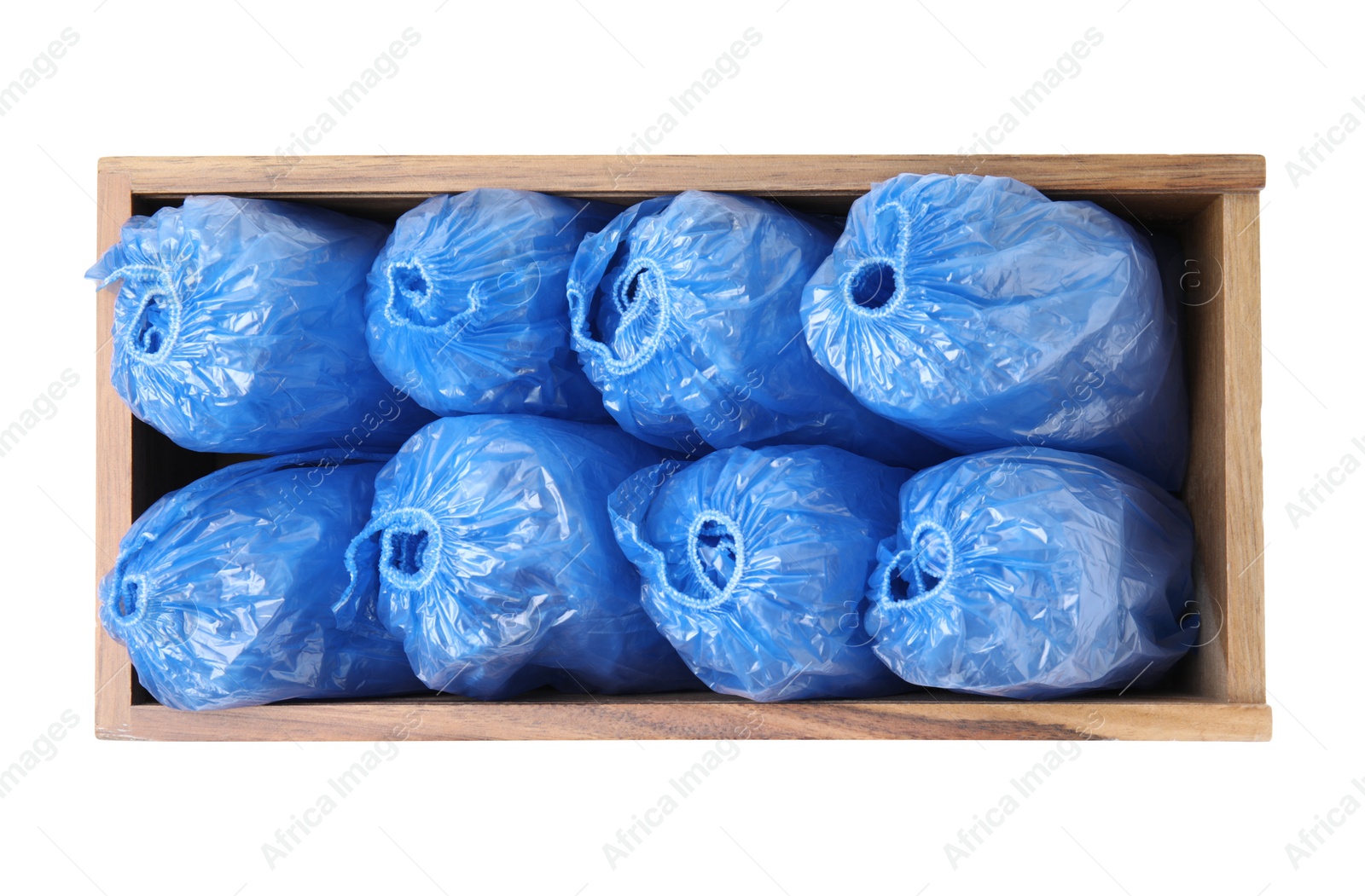 Photo of Rolled blue shoe covers in wooden crate isolated on white, top view