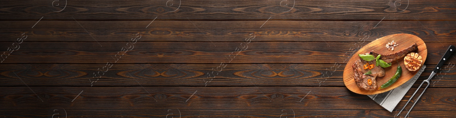 Image of Roasted beef steak with spices and meat fork on wooden table, top view. Banner design and space for text