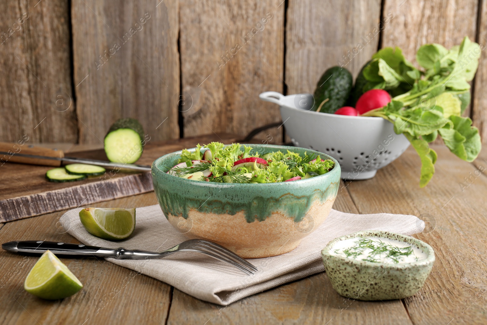 Photo of Delicious salad with radish, lettuce and dill served on wooden table