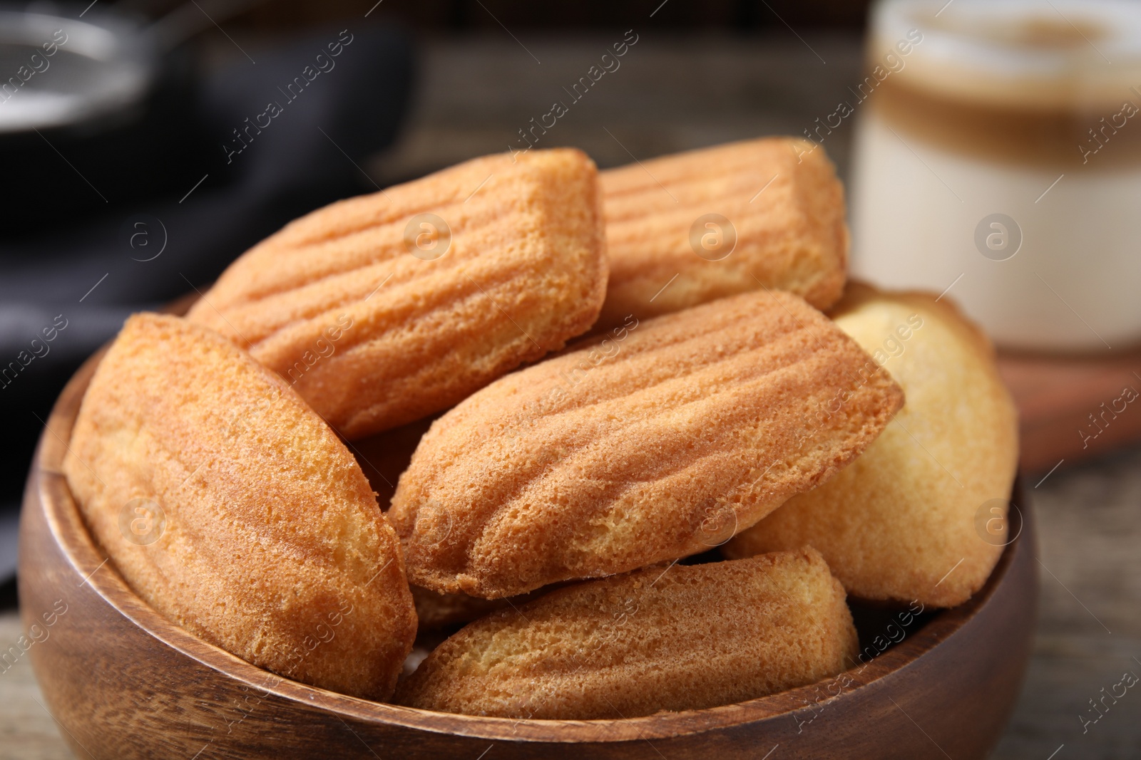 Photo of Tasty madeleine cookies in wooden bowl, closeup