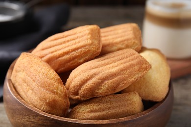 Photo of Tasty madeleine cookies in wooden bowl, closeup