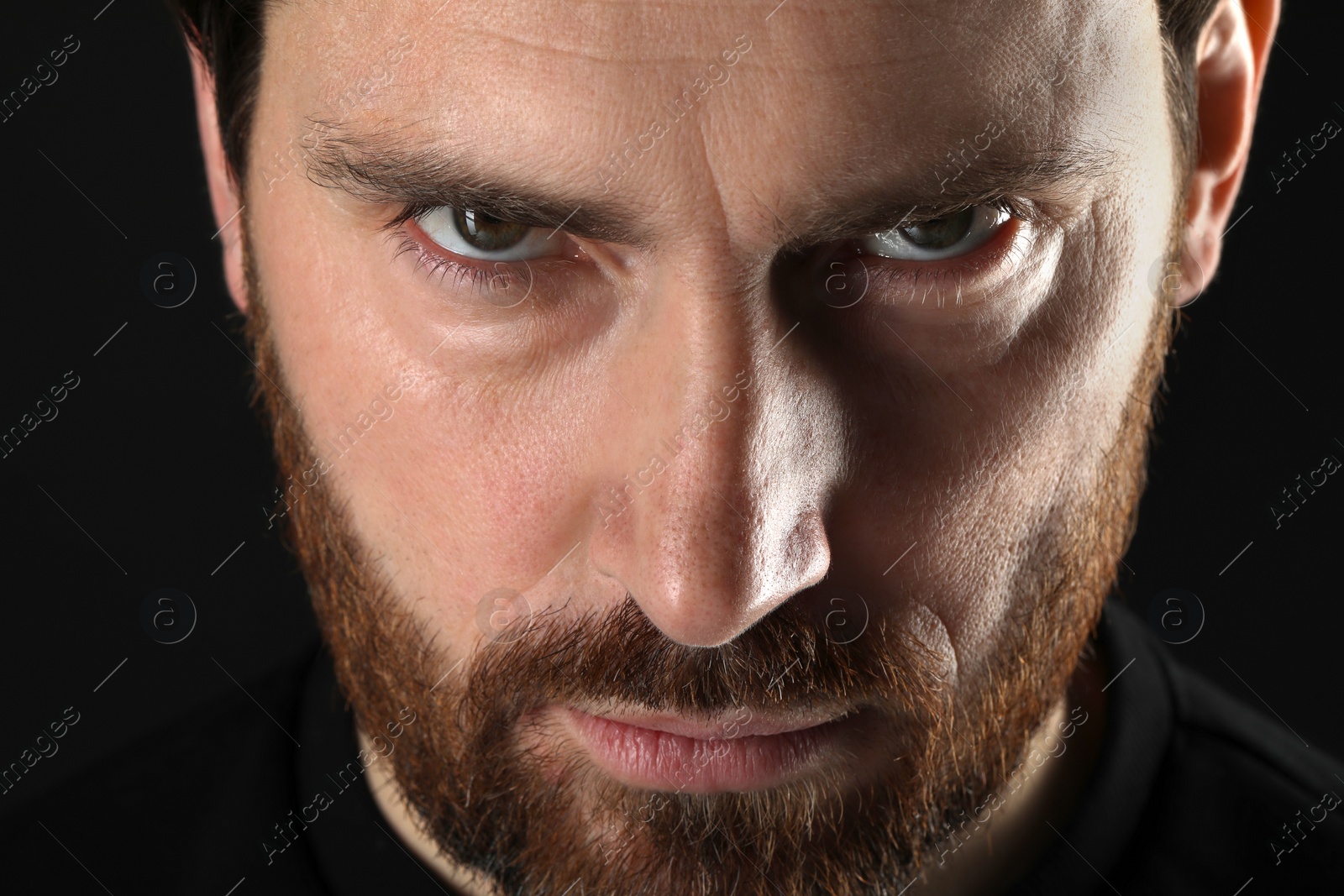 Photo of Evil eye. Man with scary eyes on black background, closeup