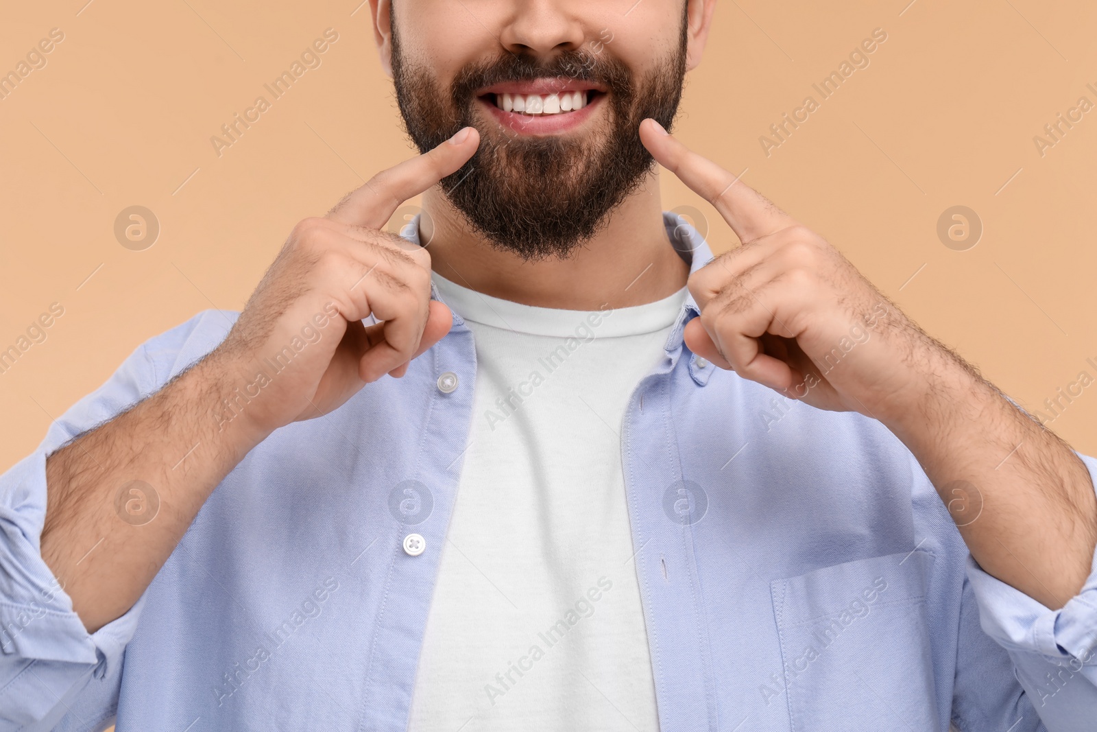 Photo of Man showing his clean teeth and smiling on beige background, closeup